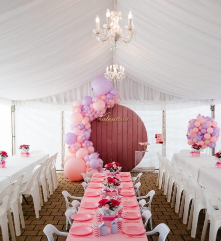 A photo of an event with a marquee setup and balloons.